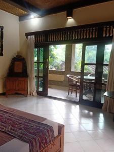 a bedroom with a bed and a large glass door at Family Guest House in Ubud