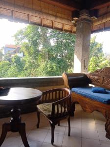 a porch with a table and chairs and a window at Family Guest House in Ubud