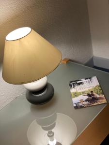 a lamp sitting on a table next to a magazine at Contact Hôtel les Platanes - Clim Mobile en Option in Villeneuve-sur-Lot