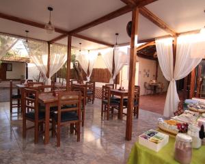 a restaurant with wooden tables and chairs and white drapes at Anka Hostel in San Pedro de Atacama