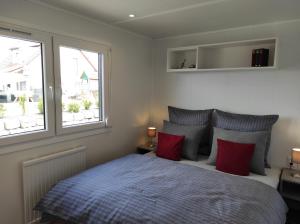 a bedroom with a bed with red pillows and two windows at Mobilheim am Geisberg in Wiesenbronn