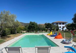 a swimming pool with chairs and a house in the background at Residence Il Pavone in Marina di Campo