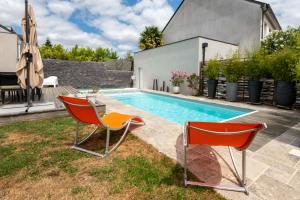 a backyard with a swimming pool and two chairs at Belle maison familiale et contemporaine avec piscine in Nantes