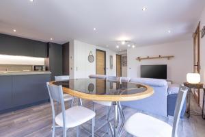 cocina y sala de estar con mesa de cristal y sillas en Le Samance 2 en Le Grand-Bornand