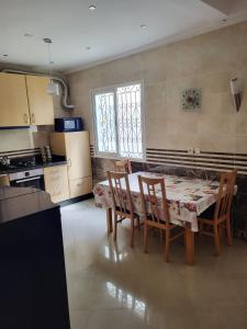 90 qm Wohnung mit 2 Schlafzimmern في مراكش: مطبخ مع طاولة وكراسي في غرفة