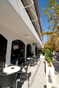 een patio met tafels en stoelen buiten een gebouw bij Aegeon Hotel - Adults Only in Kos-stad