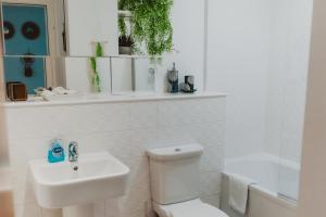 a white bathroom with a toilet and a sink at Lovely Bohemian Apartment in Heart of City Life in Glasgow