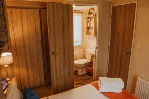 a small bathroom with a bed and a toilet at Cosy Caravan Craig Tara in Ayr