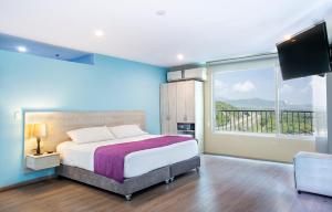 a bedroom with a large bed and a large window at Santorini Kima Beach Resort in Santa Marta