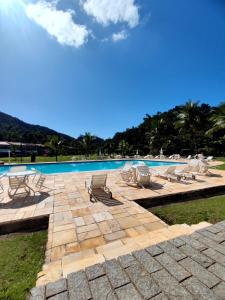a swimming pool with lounge chairs next to a swimming pool at Apartamento até 10 pessoas na enseada Guarujá em condomínio clube praia piscinas salão jogos quadra futebol campo parquinho brinquedos Wi-fi Home office in Guarujá