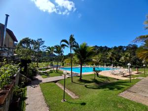 a pool at a resort with palm trees at Apartamento até 10 pessoas na enseada Guarujá em condomínio clube praia piscinas salão jogos quadra futebol campo parquinho brinquedos Wi-fi Home office in Guarujá