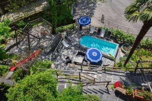 einen Blick über einen Pool mit blauem Regenschirm in der Unterkunft Rustici della Verzasca Ferien Wohnungen in Vogorno