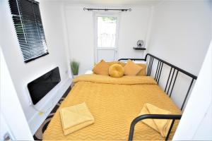 a bedroom with a bed with a yellow blanket at Adorable 1 bedroom guest house with free parking. in Bromley