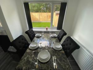 a dining room table with plates and silverware on it at Entire Luxury Holiday Home leeds in Beeston
