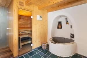 ein Bad mit einer Badewanne in einem Zimmer mit Holzwänden in der Unterkunft Rustici della Verzasca Ferien Wohnungen in Vogorno