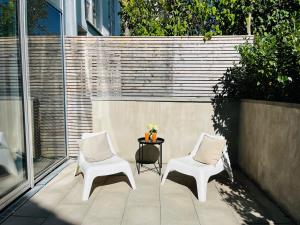 two white chairs and a table on a patio at FeWo Silberberg im Loftstil mit Terrasse in Leonberg