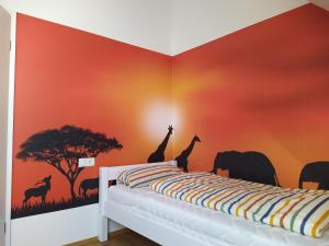 um quarto com paredes cor de laranja com girafas e árvores em Ferienhof Dachsberg Wohnung Maritim em Bermatingen