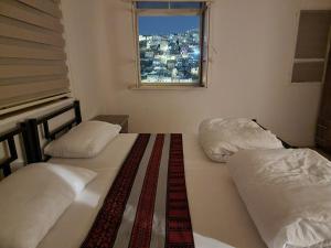 two twin beds in a room with a window at Rainbow House in Amman