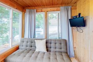 a couch in a room with a tv and windows at Cozy Lakefront Suite in Standish