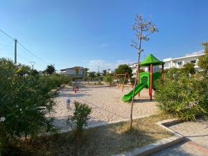 a playground with a green slide in the sand at Villa Luan Ksamil in Ksamil
