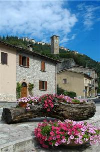 un edificio con fiori di fronte a un palazzo con torre dell'orologio di Residence il giardino sul fiume Nera a Cerreto di Spoleto
