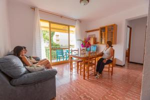 two women are sitting in a living room at Apartamentos El Oasis in Benicarló