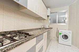a kitchen with a stove and a washing machine at Apartamentos El Oasis in Benicarló