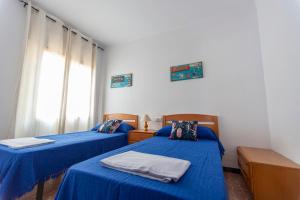 a room with two beds with blue sheets and a window at Apartamentos El Oasis in Benicarló