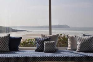 a couch with pillows and a view of a beach at Gorgeous Apartment only yards from Polzeath Beach in Wadebridge