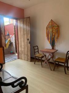 a living room with a table and chairs and a door at Chalé das Flores in Tiradentes