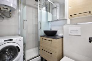 een kleine badkamer met een wastafel en een wasmachine bij Beautiful modern studio with a view on the ocean - Biarritz - Welkeys in Biarritz