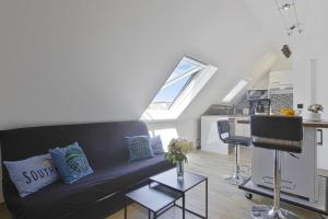 een woonkamer met een zwarte bank en een keuken bij Beautiful modern studio with a view on the ocean - Biarritz - Welkeys in Biarritz
