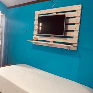 a tv on a blue wall in a bedroom at Portal Cores in Porto De Galinhas