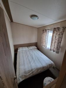 a small bedroom with a bed and a window at Willow-Static Caravan on Holiday Park near Margate, Kent in Kent