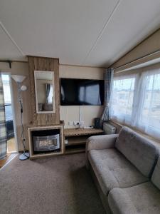 a living room with a couch and a flat screen tv at Willow-Static Caravan on Holiday Park near Margate, Kent in Kent