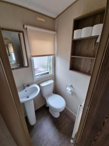 a small bathroom with a toilet and a sink at Willow-Static Caravan on Holiday Park near Margate, Kent in Kent