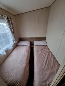 a small room with two beds and a window at Willow-Static Caravan on Holiday Park near Margate, Kent in Kent