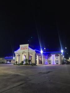 een gebouw met blauwe lichten op een parkeerplaats 's nachts bij Best Price Motel & Suites in Orange