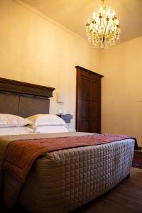 a bedroom with a large bed with a chandelier at Maison Flipot in Torre Pellice