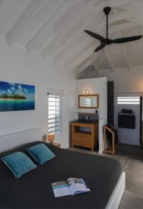 Villa La Vue - Vue panoramique sur les lagons في غوستافي: غرفة نوم بسرير ومروحة سقف