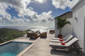 una terrazza con sedie, una piscina e l'oceano di Villa La Vue - Vue panoramique sur les lagons a Gustavia
