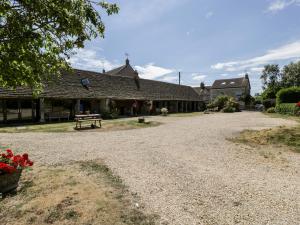 a gravel road in front of a building with a bench at Tump Cottage in Nympsfield