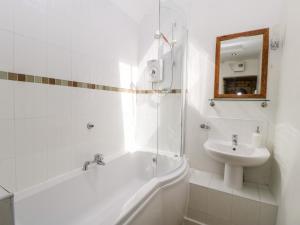 a white bathroom with a sink and a tub and a mirror at Tump Cottage in Nympsfield