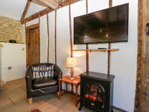 a living room with a fireplace and a flat screen tv at Nympy Cottage in Nympsfield