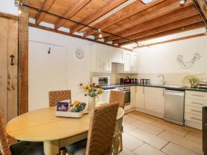una cucina con tavolo e sedie in legno e una cucina con armadietti bianchi di Nympy Cottage a Nymphsfield