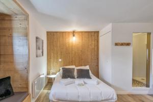sypialnia z białym łóżkiem i drewnianą ścianą w obiekcie Studio Loup - L'Igloo - Welkeys w mieście Combloux
