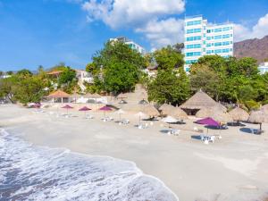 a beach with chairs and umbrellas and buildings at Hotel Santorini Casablanca in Santa Marta