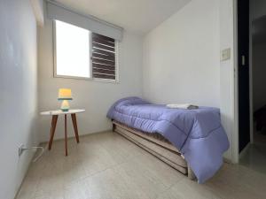 Dormitorio pequeño con cama púrpura y mesa en Apartamento Lela en Mendoza