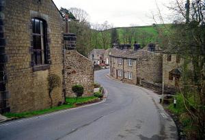 an empty street in a village with stone houses at Poppy's Place in Oakworth