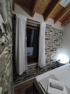 a bedroom with a window with white curtains and a tv at dolihis gi "loupastra"kampos ikaria in Évdhilos